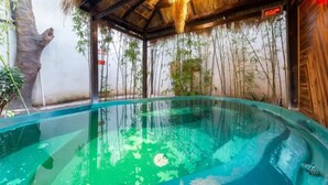 A hot tub with a bamboo backdrop and a wooden structure overhead. - Floral Hotel Yun Jing He Yuan Haidong (Haidong)