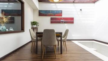 A dining area with a wooden floor, a table with four chairs, and two wall-mounted paintings.