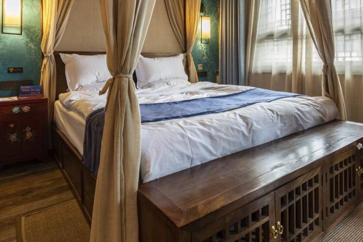 A four-poster bed with a wooden headboard, white linens, and a blue throw blanket.