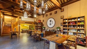 A cozy, rustic interior with exposed wooden beams, a central wooden table, and shelves filled with various items. - Floral Hotel Yun Jing He Yuan Haidong (Haidong)