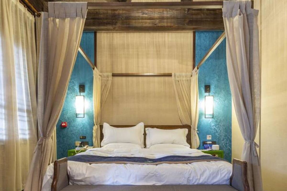 A four-poster canopy bed with white linens, wooden frame, and two bedside lamps.