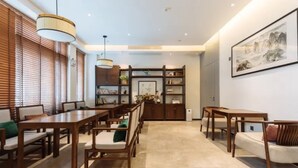 Un comedor espacioso con mobiliario de madera, una estantería central y una obra de arte grande enmarcada en la pared.