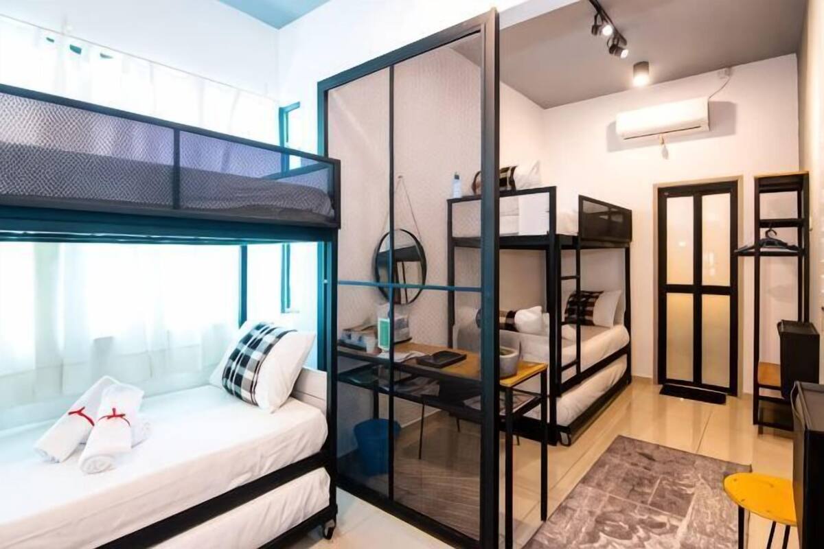 A compact room with bunk beds, a desk, a chair, and a small table.
