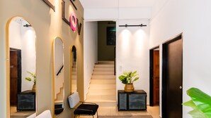 A modern hallway with a staircase, a seating area with a sofa and chairs, and a potted plant. - The Lov Penang (George Town)