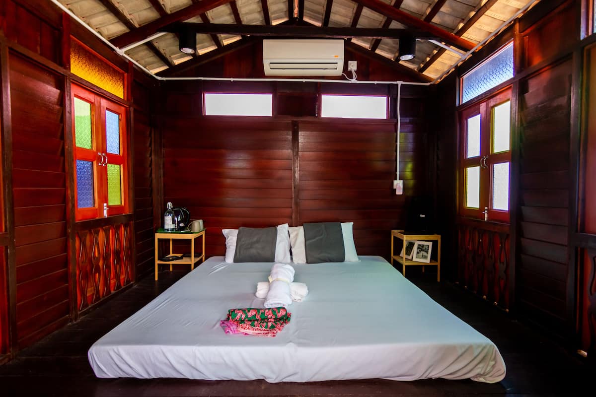 A large bed with white linens, two nightstands with lamps, and a window with a view.