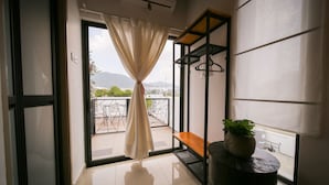 A room with a sliding glass door leading to a balcony with a view of mountains. - The Lov Penang (George Town)
