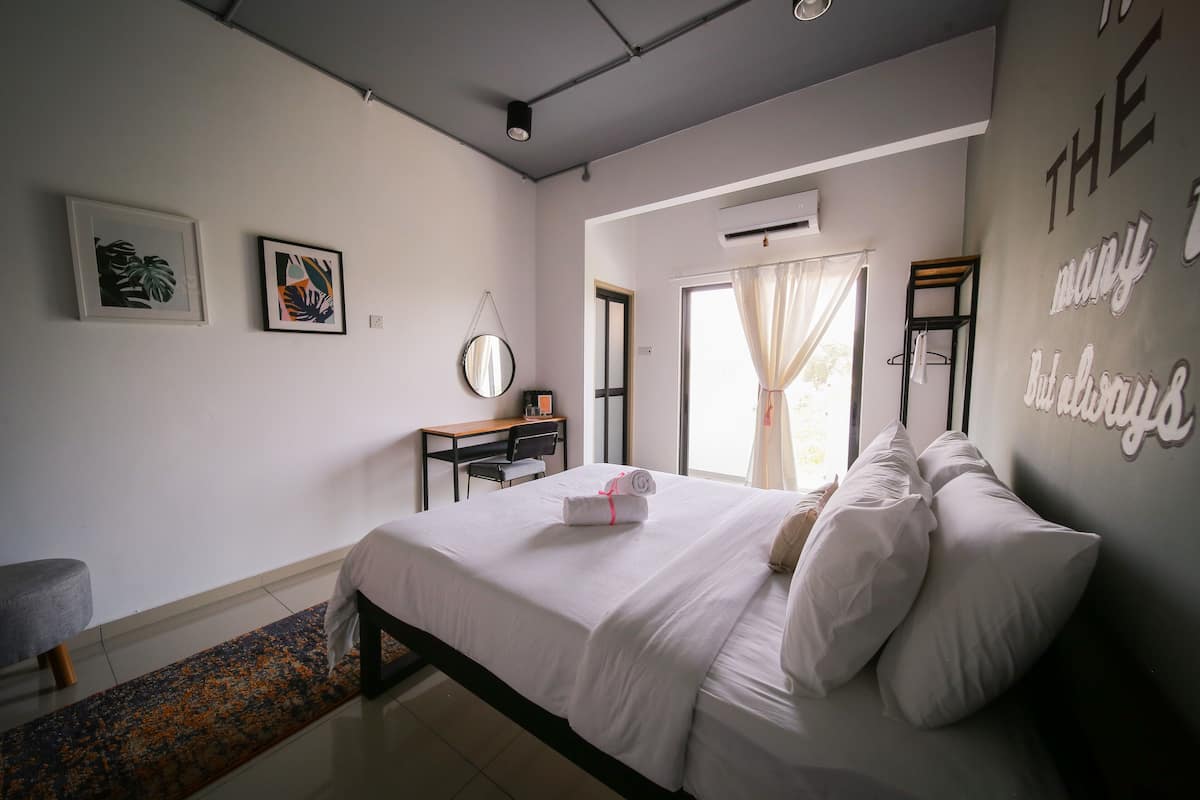 A neatly arranged bedroom with a bed, bedside table, and a desk with a chair.