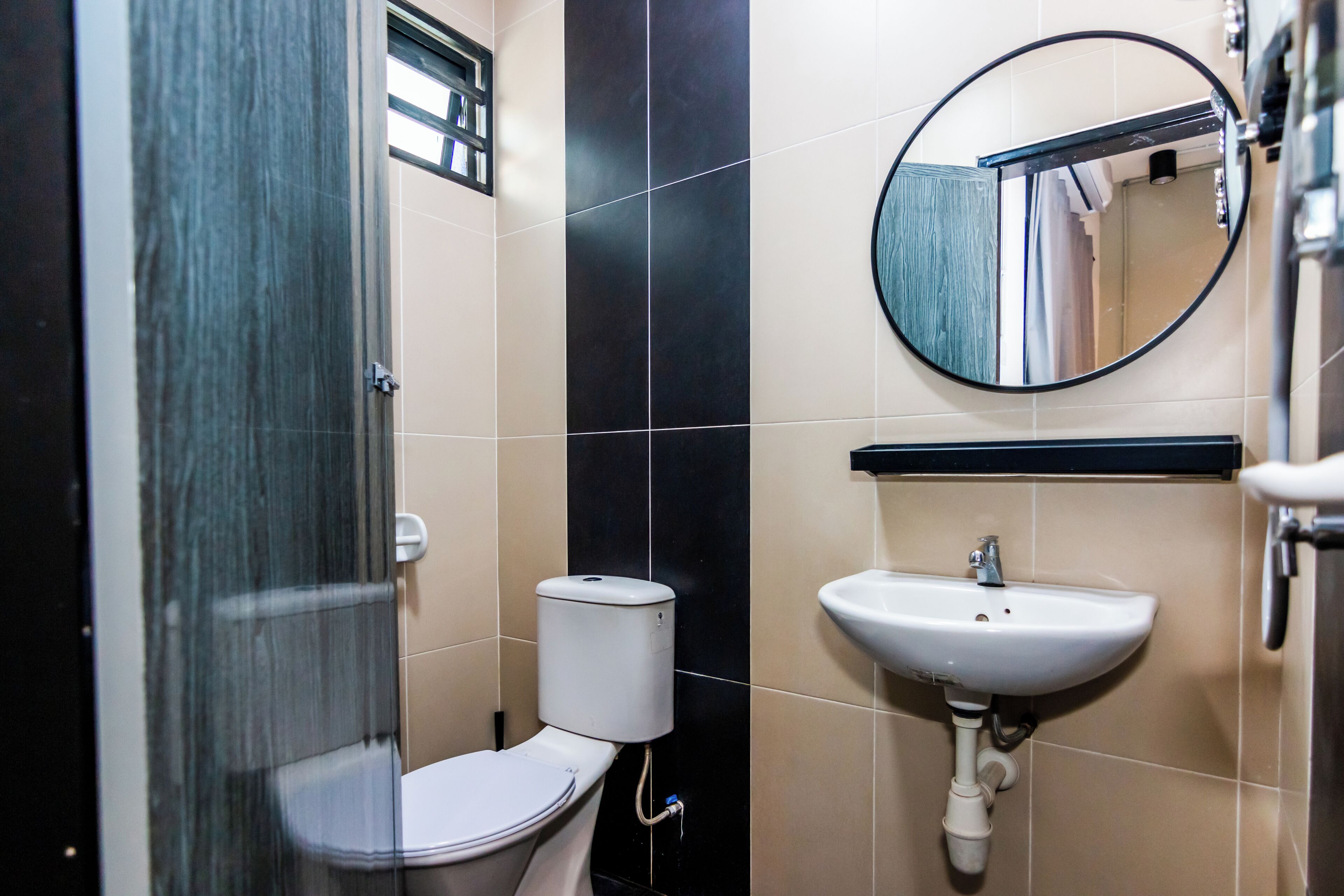 A bathroom with a toilet, sink, and mirror.