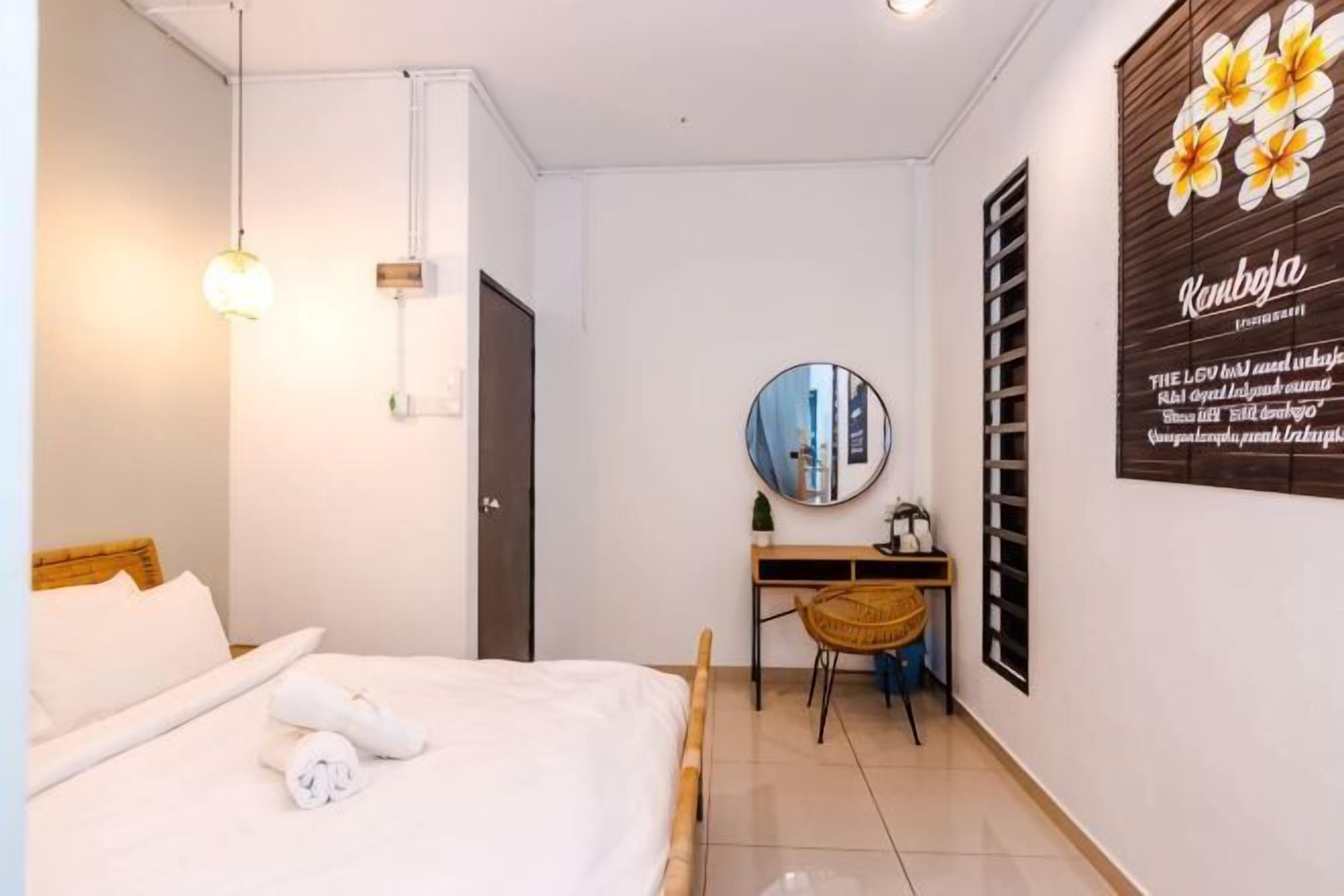 A bedroom with a bed, a desk, a chair, a mirror, and a wall-mounted artwork.