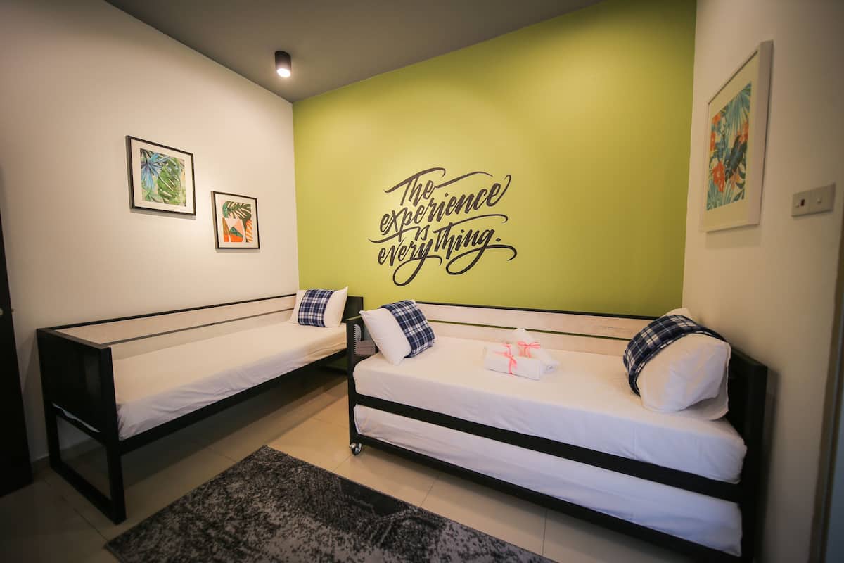 A room with two single beds, a green accent wall, and a motivational quote.