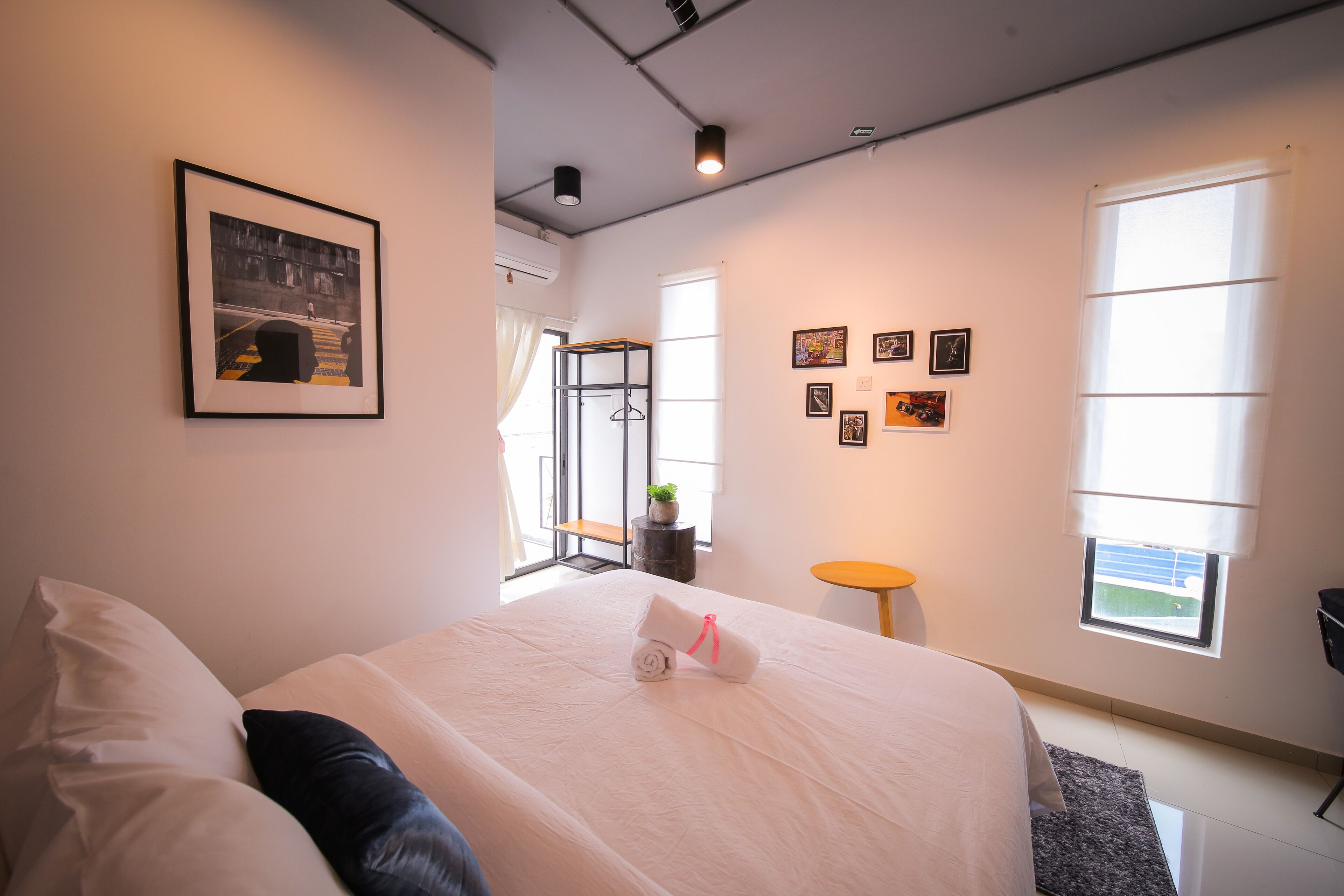 A modern hotel room with a large bed, a framed picture on the wall, and a small table with a plant.