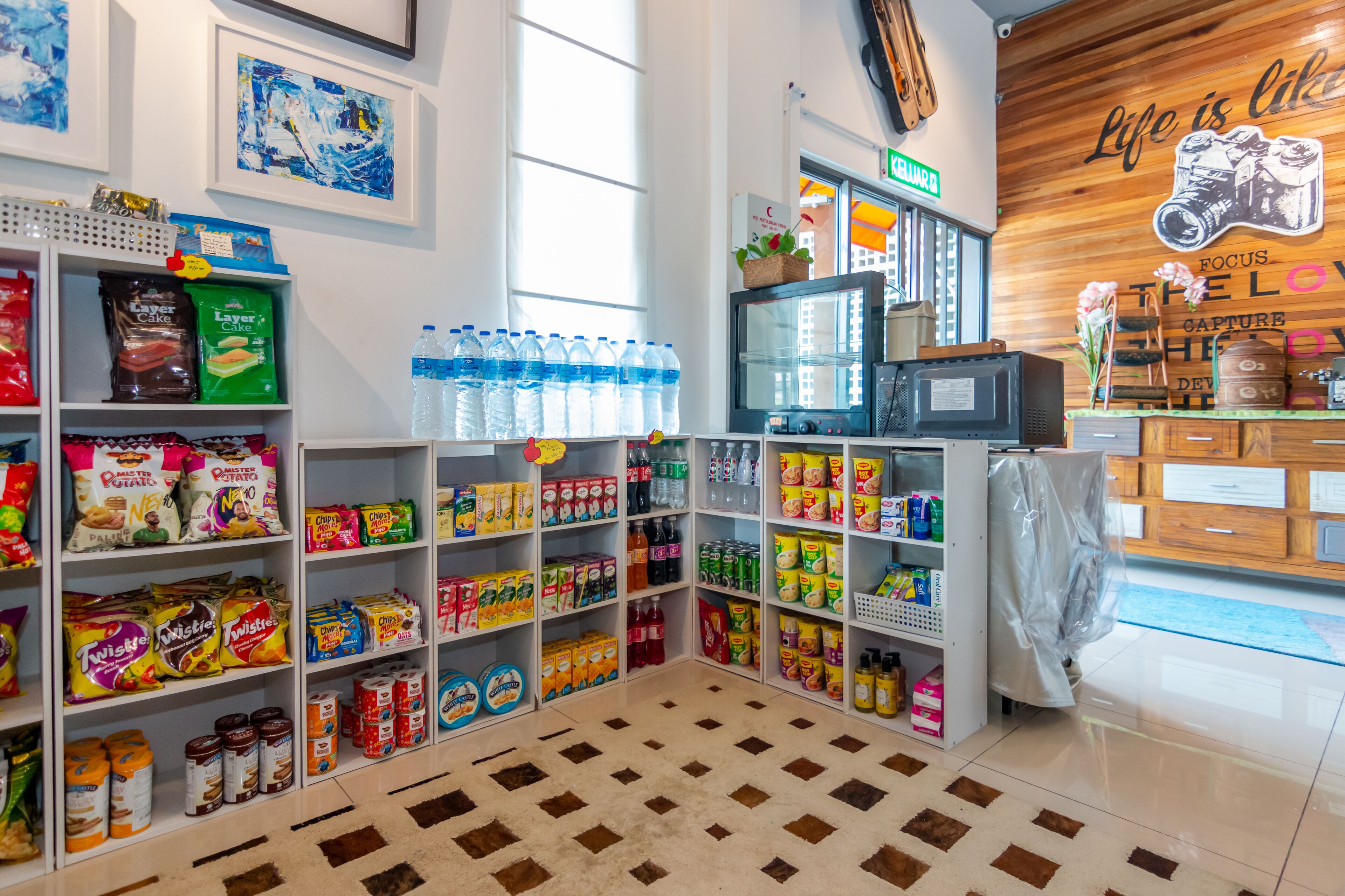 Una tienda bien organizada con estantes llenos de aperitivos, bebidas y otros productos alimenticios.