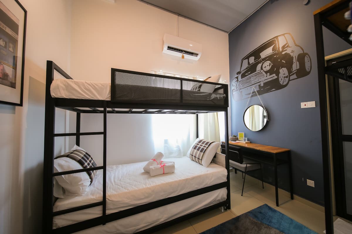 A bunk bed with a desk and chair, a mirror, and an air conditioning unit.