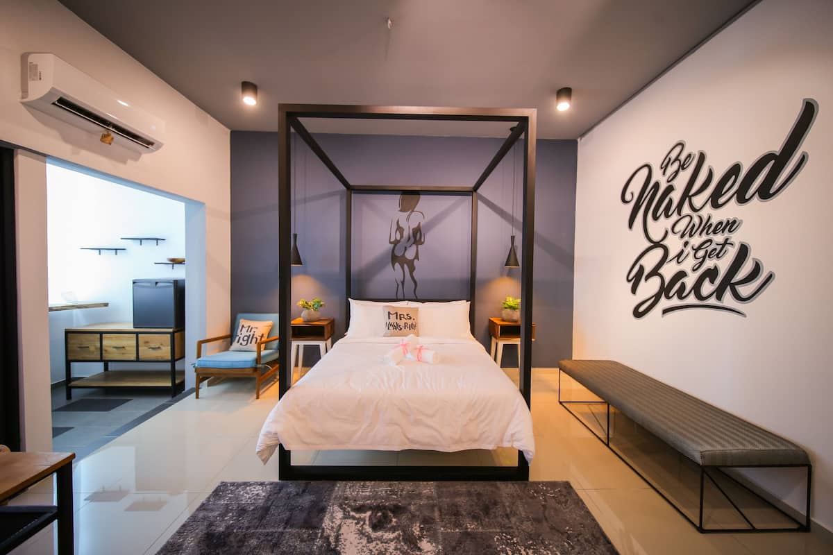 A modern bedroom with a four-poster bed, a bench, and a motivational wall quote.