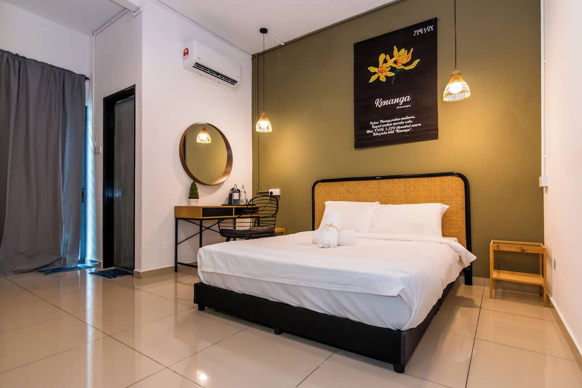 A neatly arranged hotel room with a large bed, a desk with a chair, a small table, and a wall-mounted mirror.