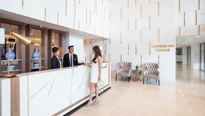 Uma área de recepção com balcão de mármore, uma placa com a inscrição "CARIBBEAN TOWER" e design de interiores moderno.