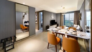 Uma sala de jantar moderna com uma mesa posta para quatro pessoas, uma televisão e vista para a cidade através de grandes janelas.