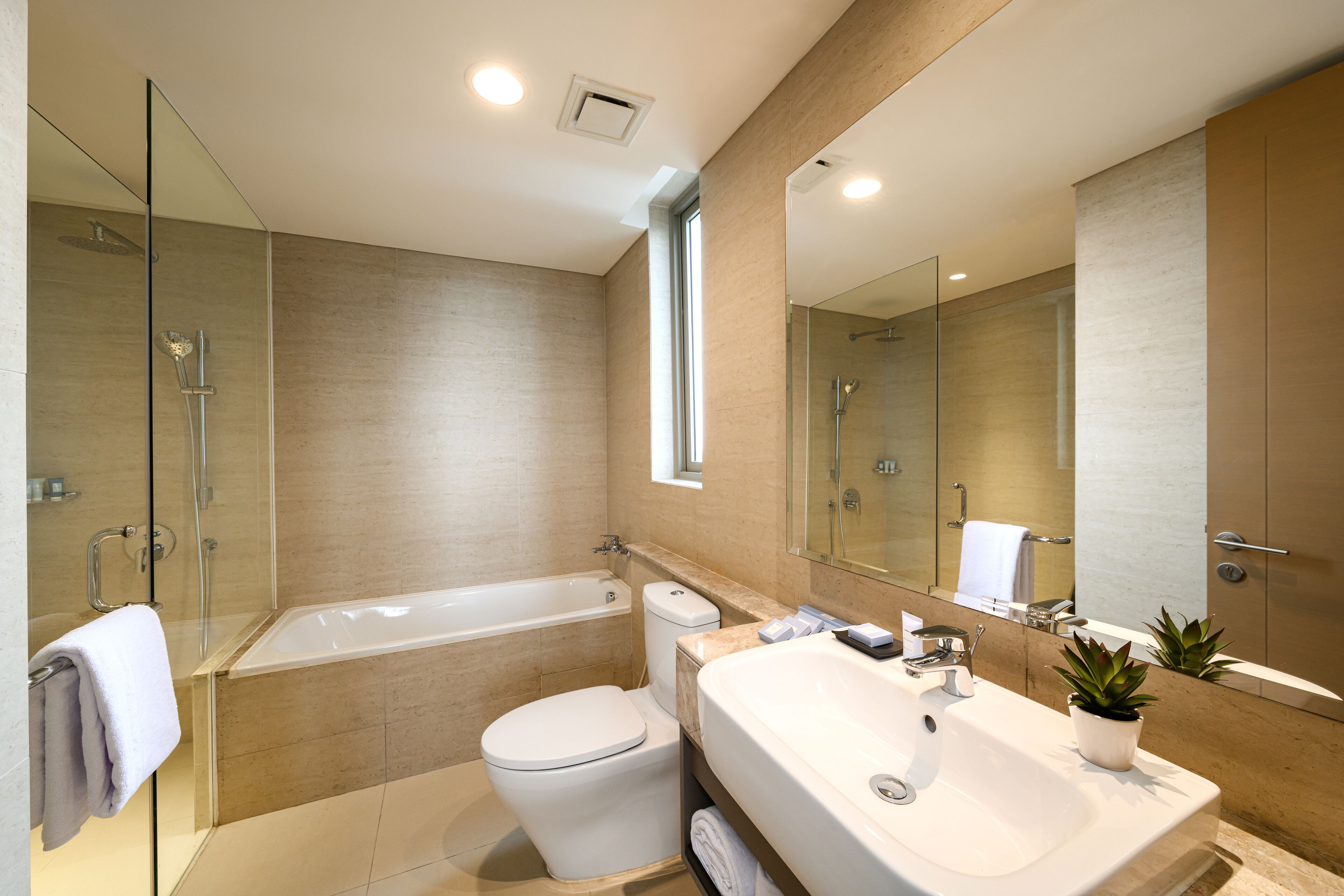 Un baño moderno con ducha acristalada, bañera independiente, inodoro y un lavabo grande con espejo.