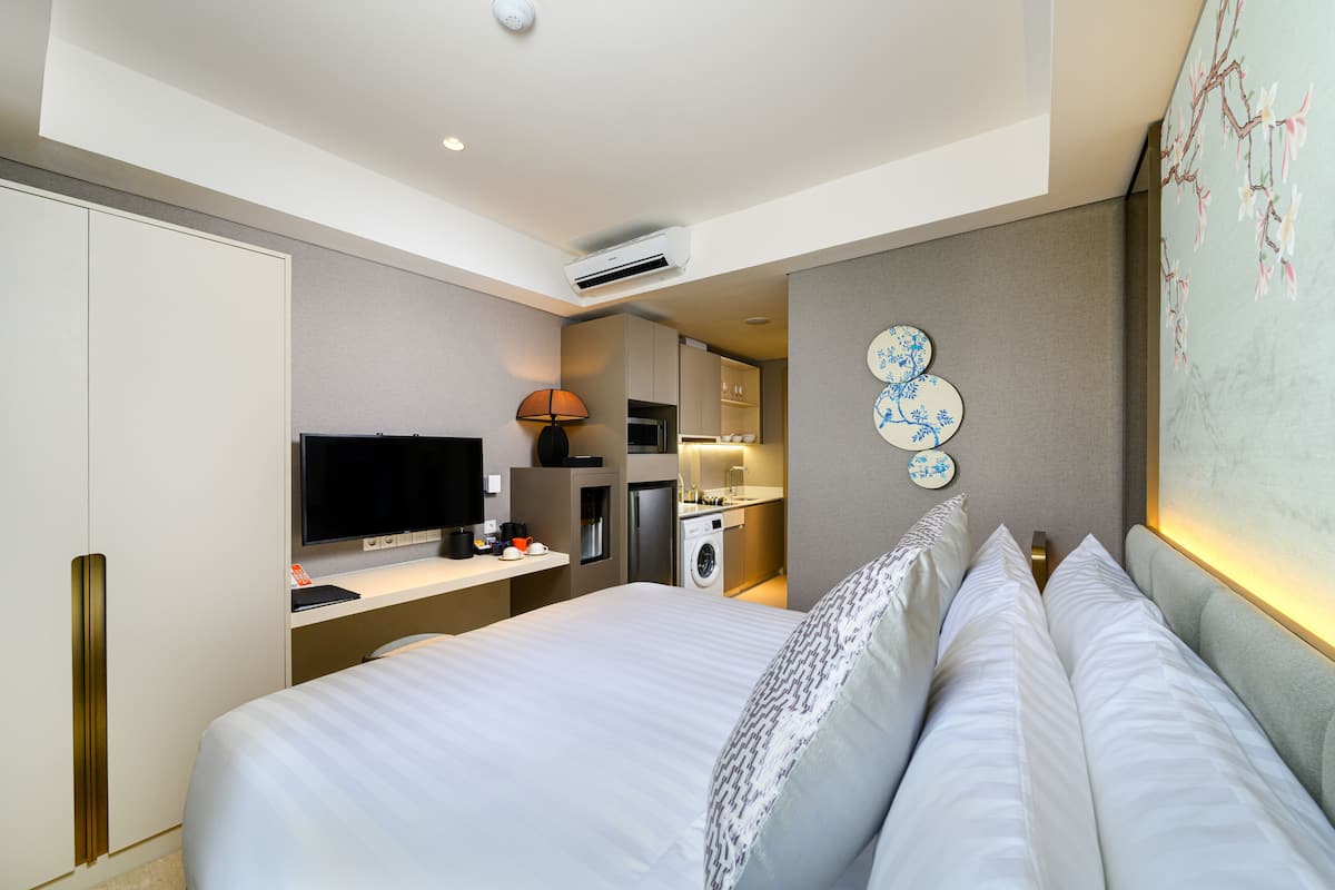 A hotel room with a bed, a television, a washing machine, and a kitchenette.