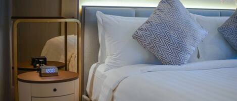 Ein Hotelzimmer mit einem Bett, einem Nachttisch mit digitaler Uhr und einem Beistelltisch.