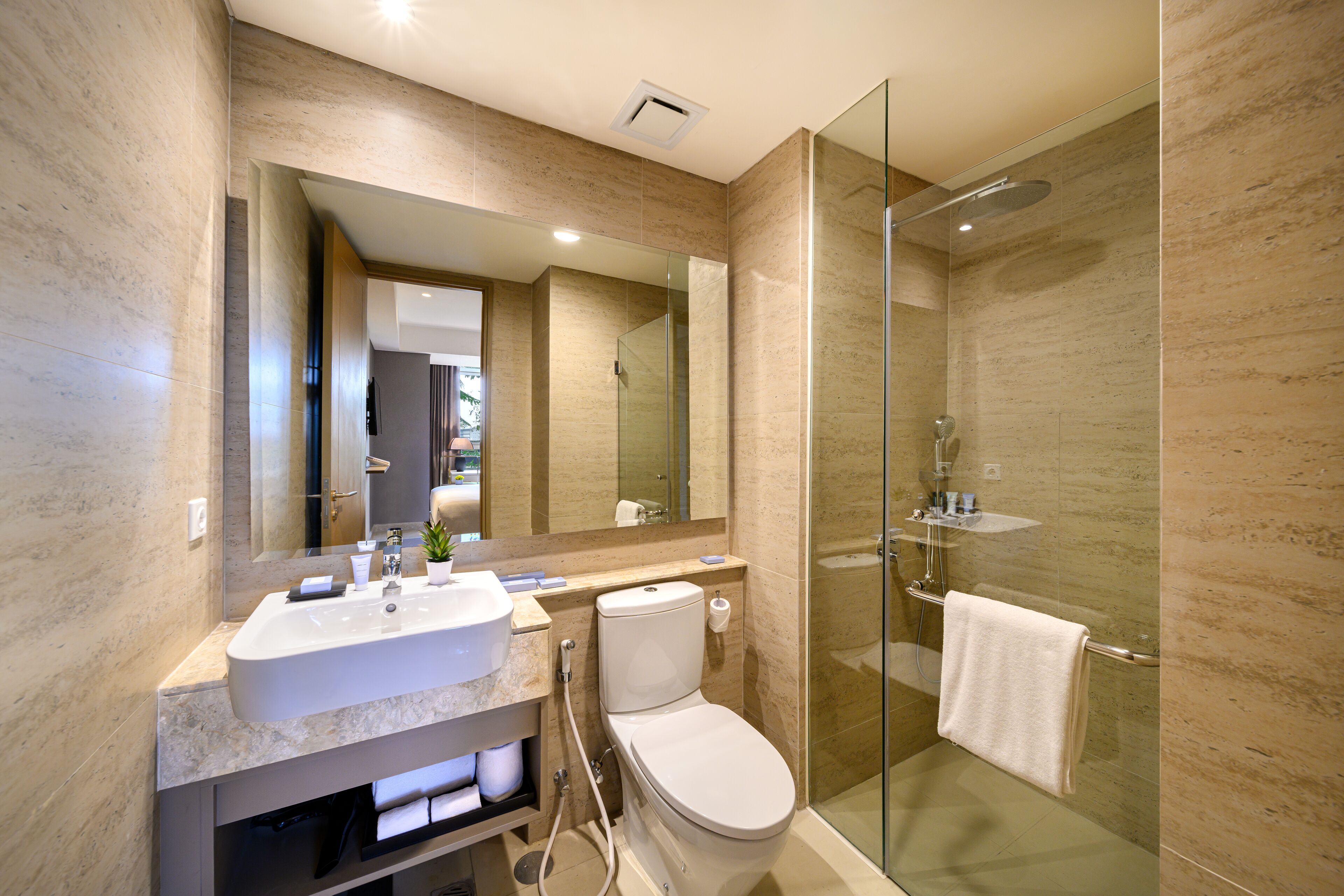 A modern bathroom with a glass-enclosed shower, a large mirror, and a vanity with a sink and toilet.