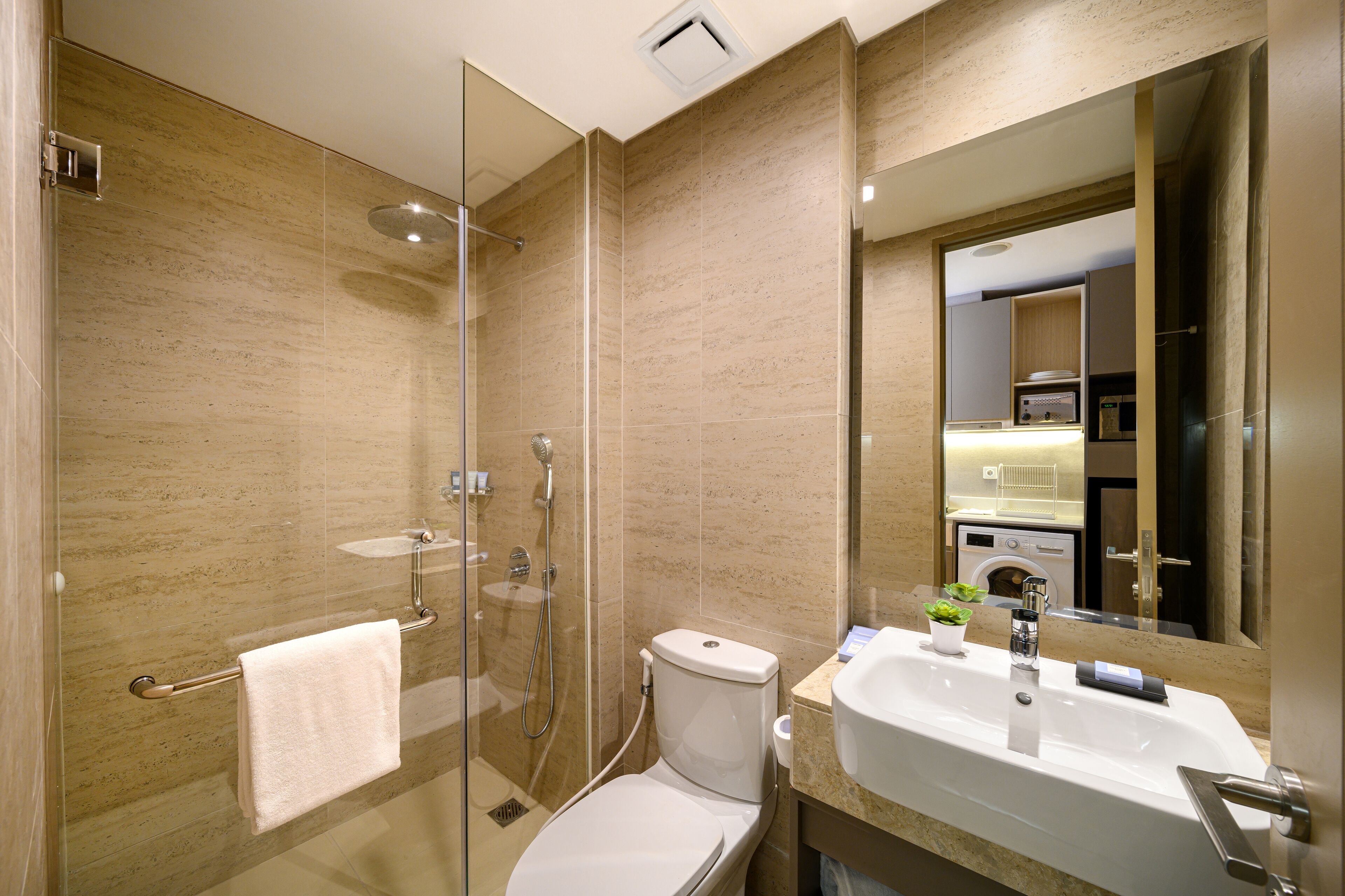 A modern bathroom with a glass-enclosed shower, a toilet, and a sink with a mirror above it.