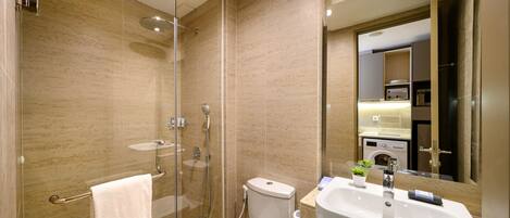A modern bathroom with a glass-enclosed shower, a toilet, and a sink with a mirror above it.