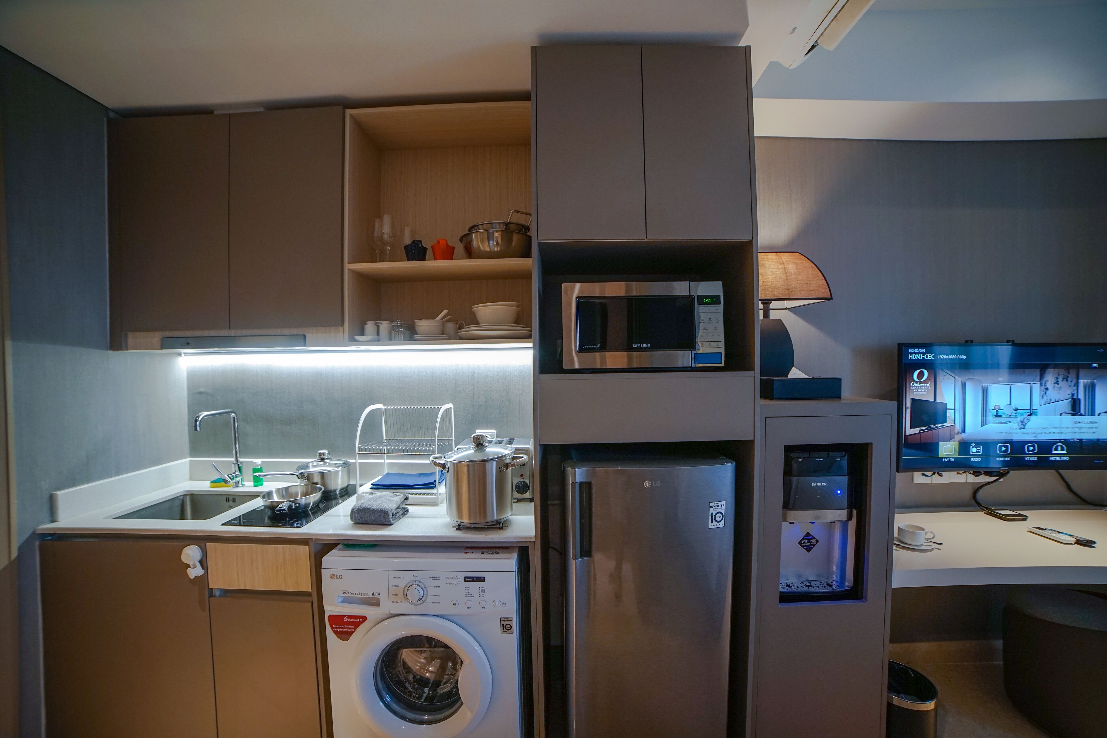 A compact kitchen with a washing machine, microwave, and refrigerator.
