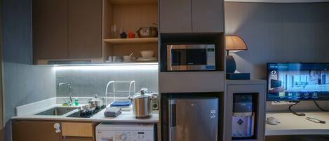 A compact kitchen with a washing machine, microwave, and refrigerator.