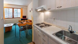 Cocina compacta con estufa a gas, un lavamanos y paredes cubiertas de azulejos blancos.