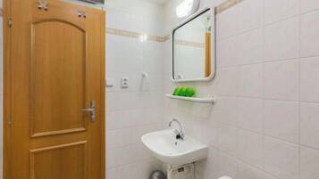 A bathroom with a wooden door, a white sink, a mirror, and a toilet.