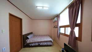 A bedroom with a bed, a television, and a window with curtains. - Daecheon Garim Pension (Boryeong)