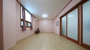 A spacious room with a wooden floor, a sliding glass door, and a small table with a chair. - Daecheon Garim Pension (Boryeong)