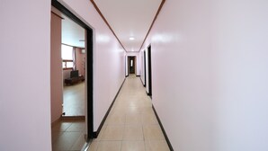 A long, narrow hallway with light pink walls and a tiled floor. - Daecheon Garim Pension (Boryeong)