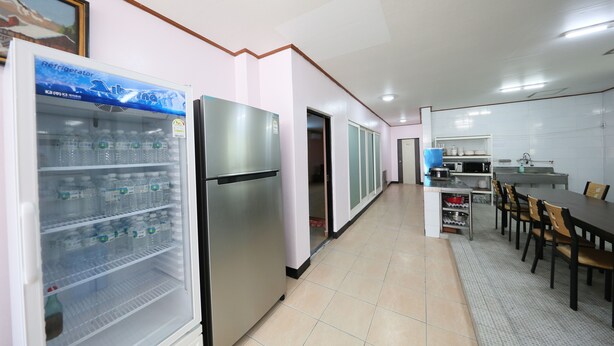 A kitchen with a refrigerator, microwave, and dining area. - Daecheon Garim Pension (Boryeong)