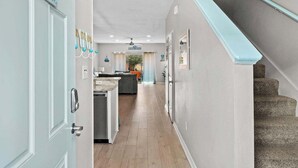 A hallway leading to a kitchen and living area with a staircase. - Gem Beach House Steps to Beach&Pool+Opt Golf Cart (Miramar Beach)