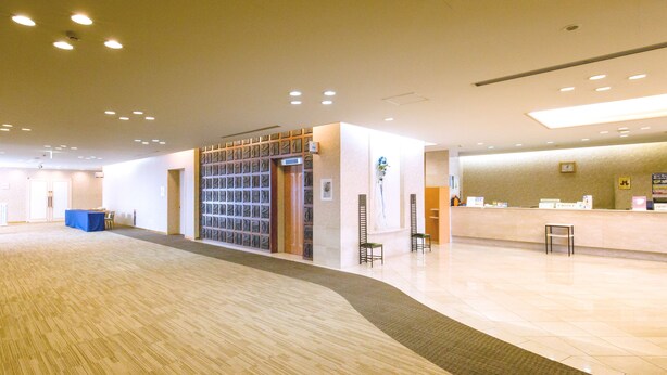 Eine geräumige Lobby mit einer Rezeption, einem blauen Tisch und einer Wand mit Musterdesign.