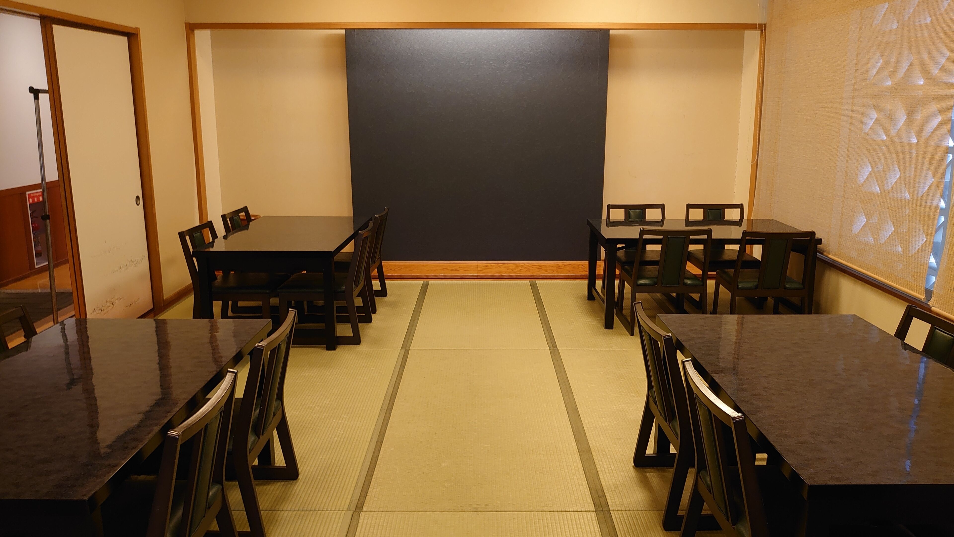 A conference room with a large blackboard, wooden tables, and chairs.