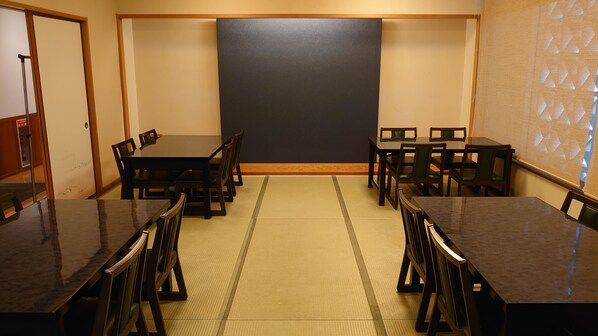 A conference room with a large blackboard, wooden tables, and chairs.