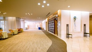 Eine geräumige Hotelhalle mit Teppichboden, einer Rezeption und einer Wand mit gerahmten Bildern.