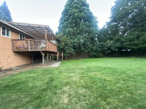 A house with a wooden deck and a large tree in the backyard.
