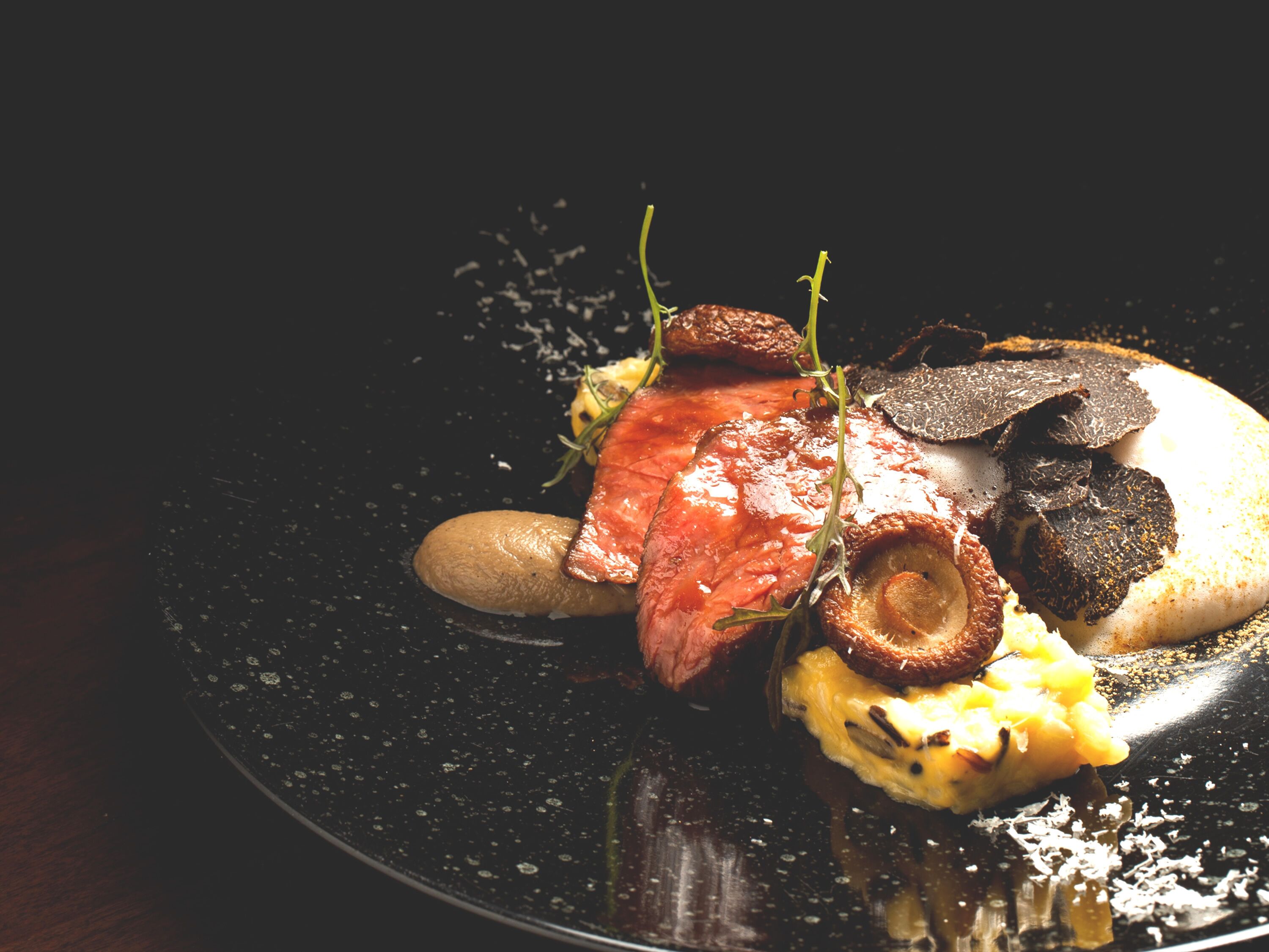A plate with a steak, mushrooms, and a creamy sauce.