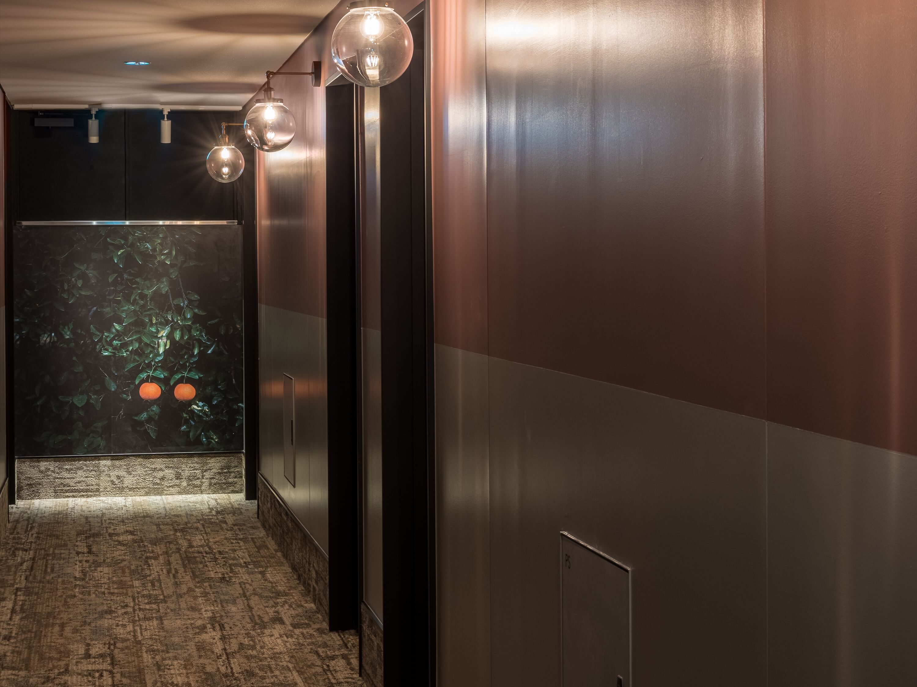 A hallway with a polished floor, a wall-mounted light fixture, and a door with a number.