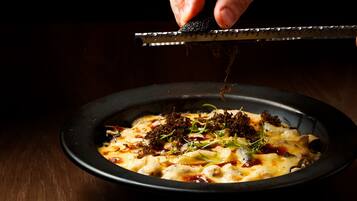 A dish with a black bowl, garnished with green herbs and topped with a dark topping.