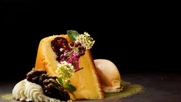 A dessert with a heart-shaped piece of cake, garnished with flowers and a dollop of cream.