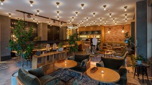 Un espacio lounge moderno con mesas redondas, sofás y una pared de ladrillo.