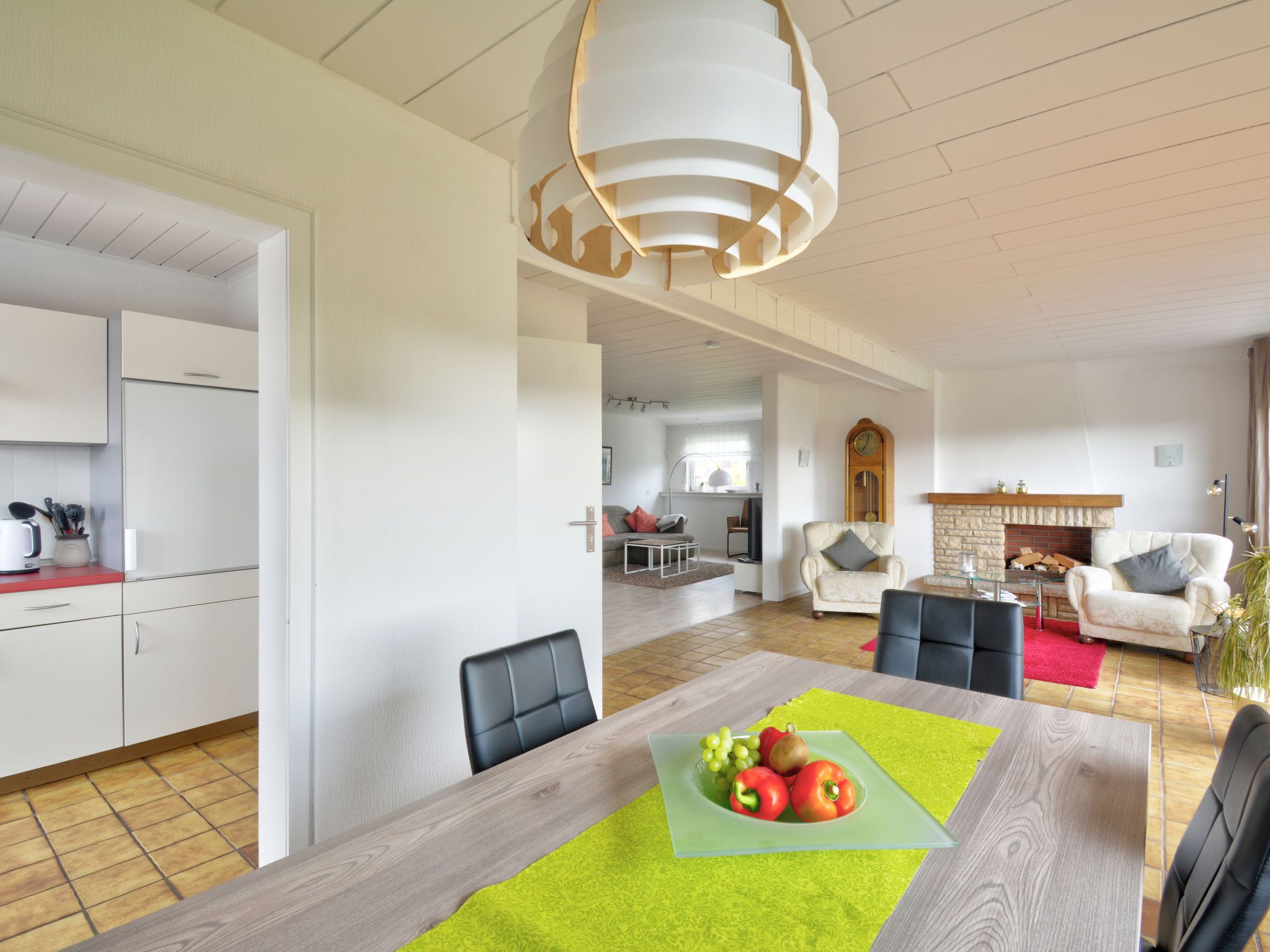 Une cuisine moderne avec des meubles blancs et un coin repas comprenant une table et des chaises en bois.