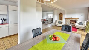 Una cocina moderna con armarios blancos y un comedor con mesa y sillas de madera.