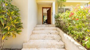 Una escalera de piedra que lleva a una puerta, rodeada de exuberante follaje y plantas en flor.