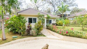 Una casa con techo de tejas, rodeada de un jardín bien cuidado con diversas plantas y flores.